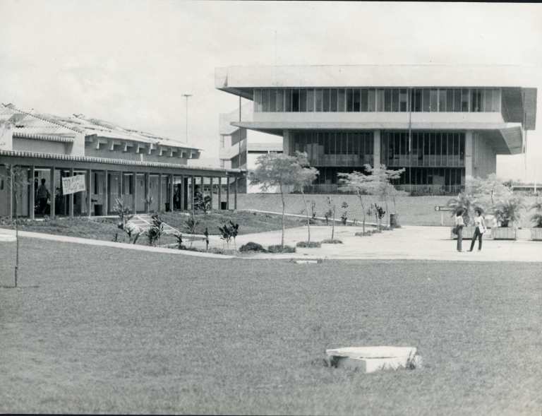 Foto antiga, em preto e branco, do campus de Goiabeiras, onde aparecem os prédios do restaurante universitário e da biblioteca central.