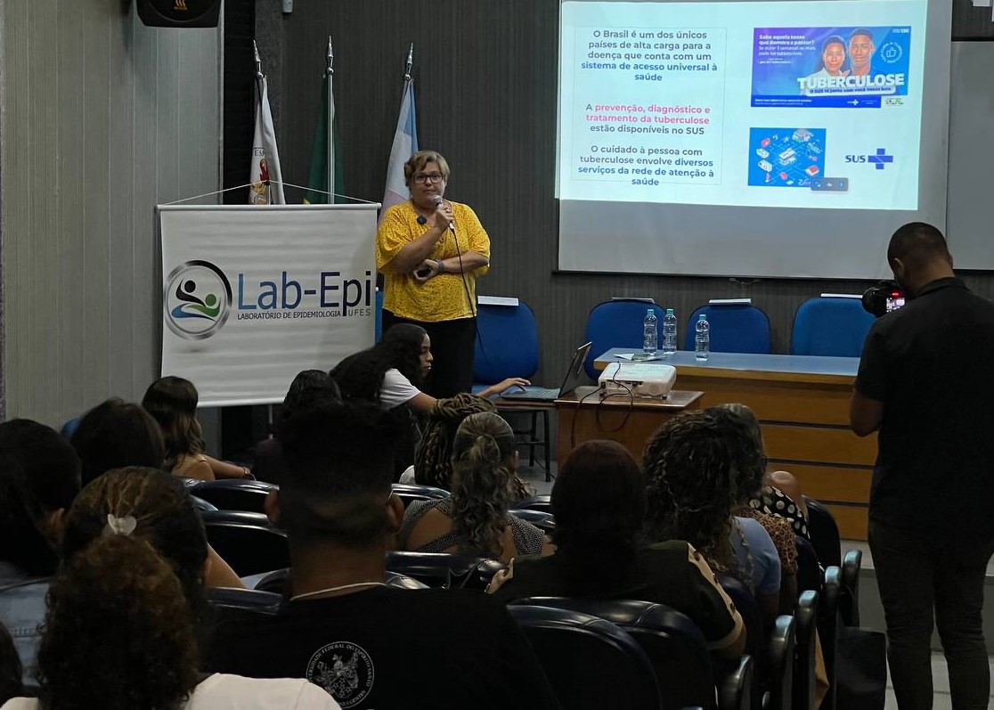 Foto do público do evento Foto do público do evento dentro do auditório, assistindo à fala de Fernanda Dockhorn, à frente, de camisa amarela.