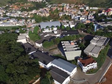 foto de prédios brancos e telhado cinza permeados de áreas verdes, área urbana  ao fundo.