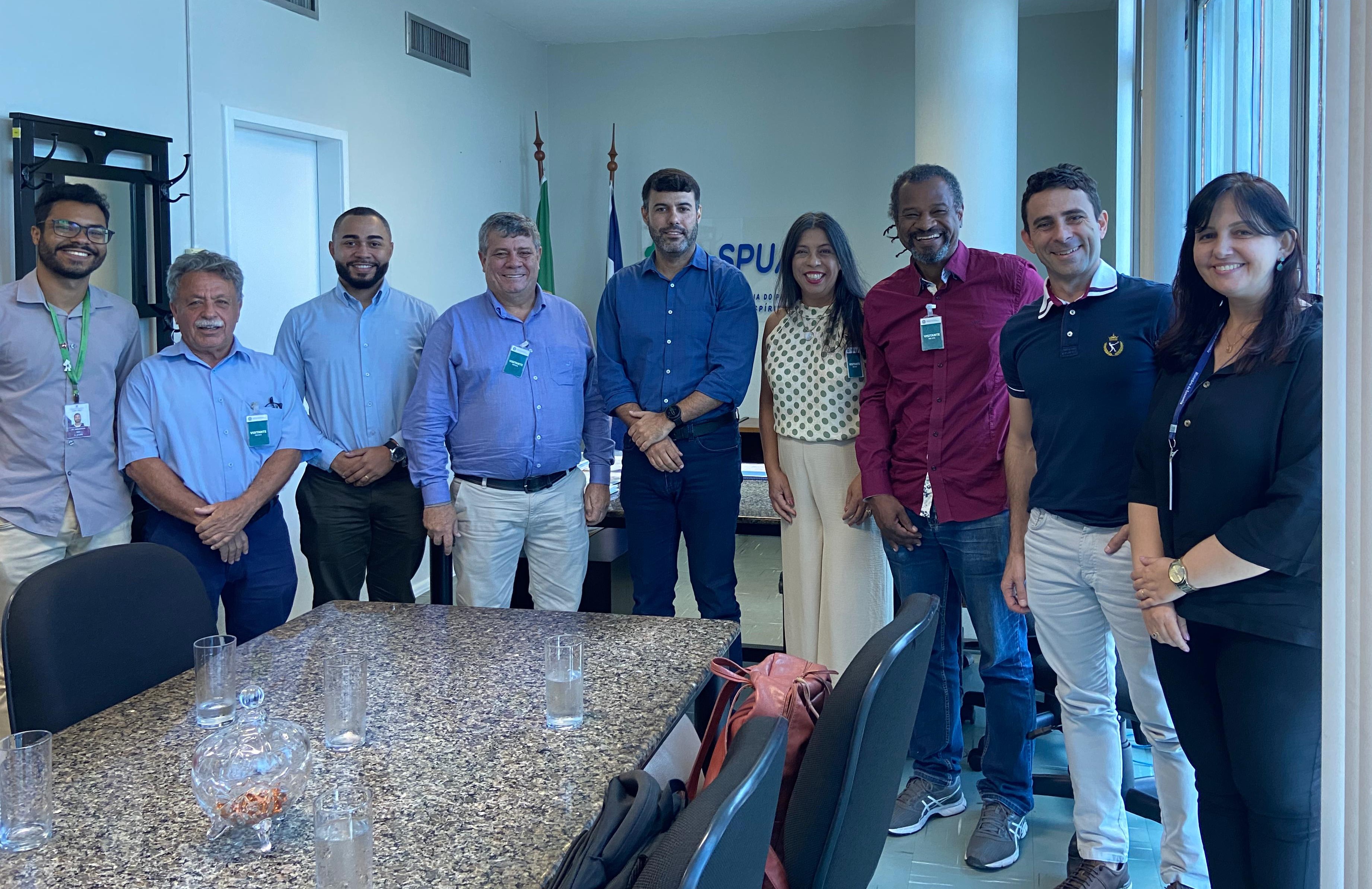 Reunião na SPU Foto da reunião na sala da SPU, com todos os presentes em pé, envolta da mesa.