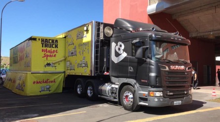 Foto do HackaTruck, um caminhão preto com carroceria amarela