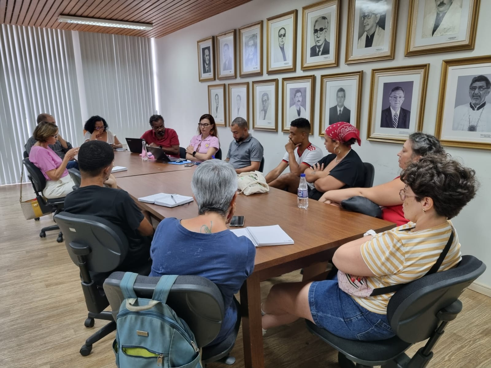 Foto da sala de reuniões da Reitoria, com todos os participantes em reunião, sentados em volta da mesa