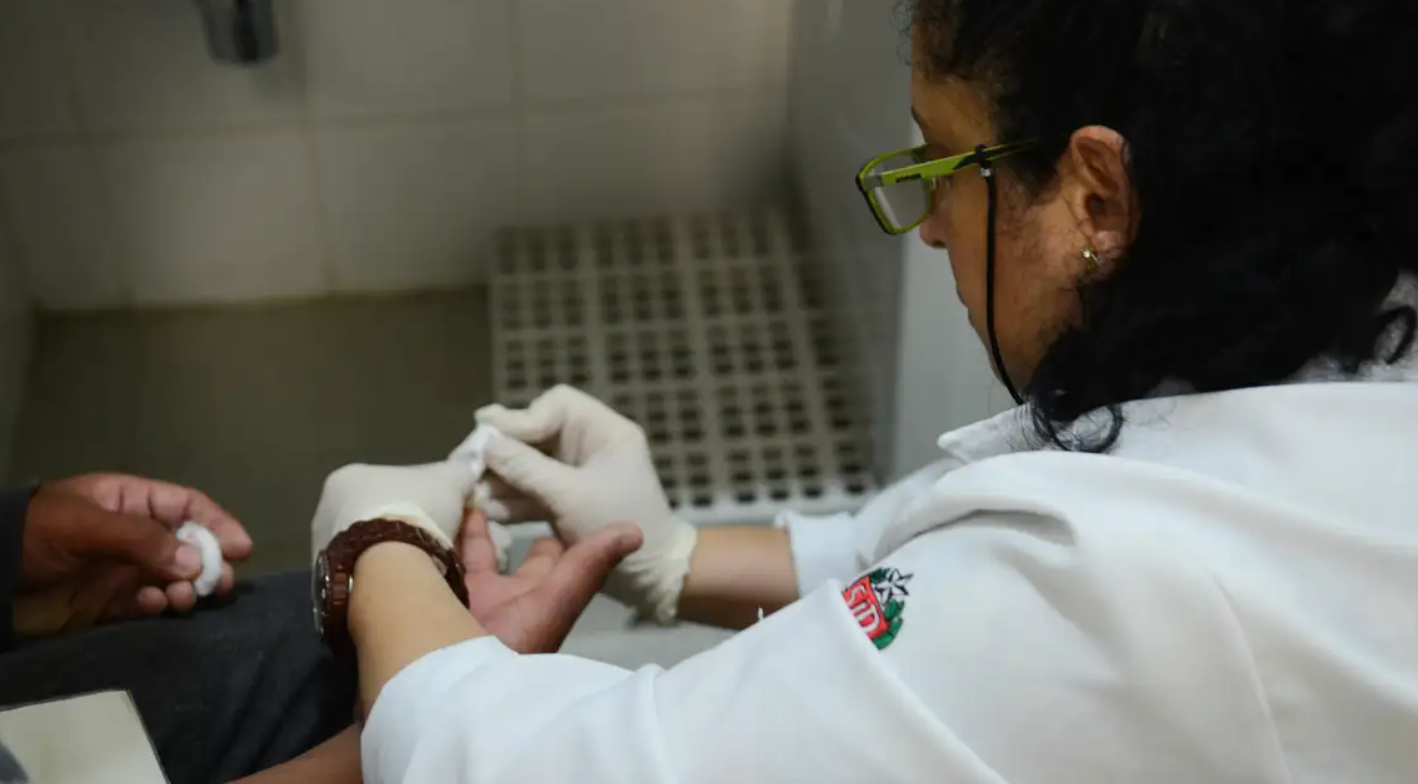 Profissional da saúde tira amostra de sangue do dedo de um paciente.