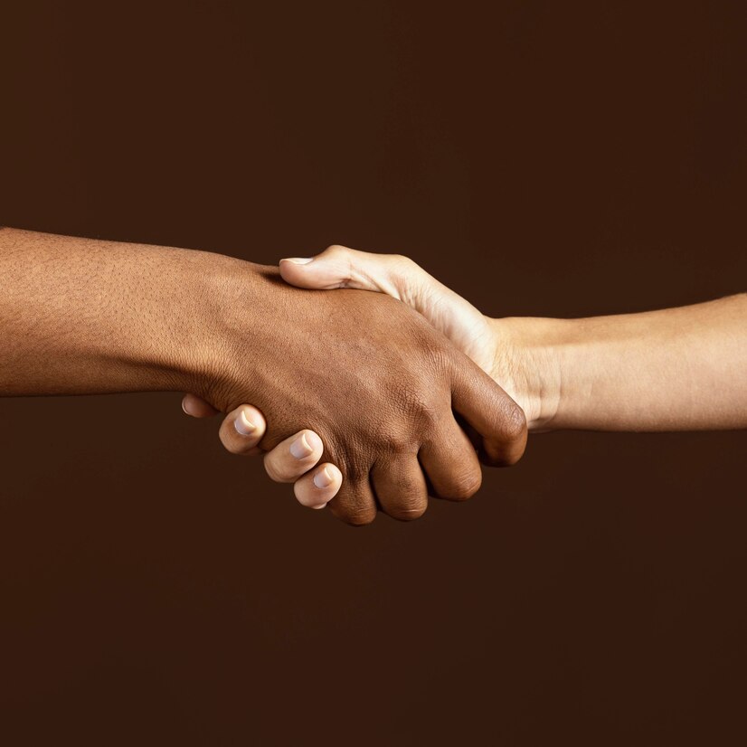 Imagem de duas mãos, uma branca e uma negra, se cumprimentando. 
