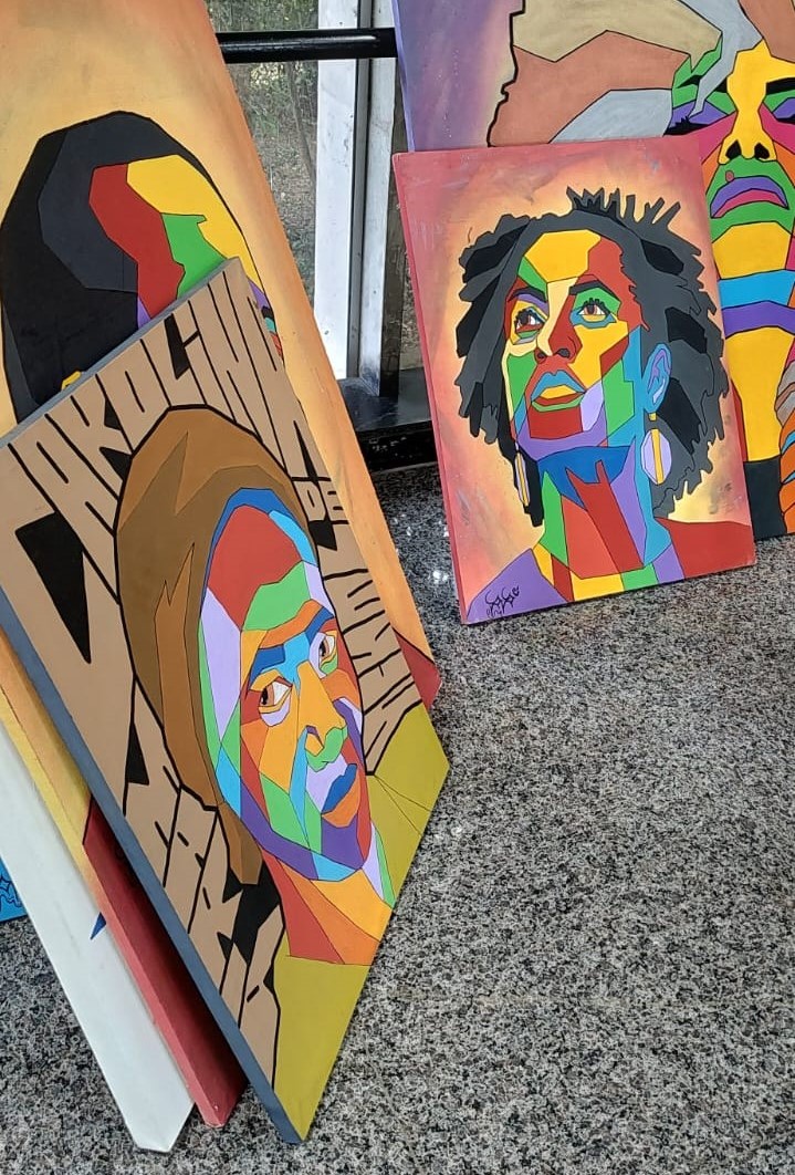 Outros quadros da exposição, dispostos em pé, encostados próximo à janela.