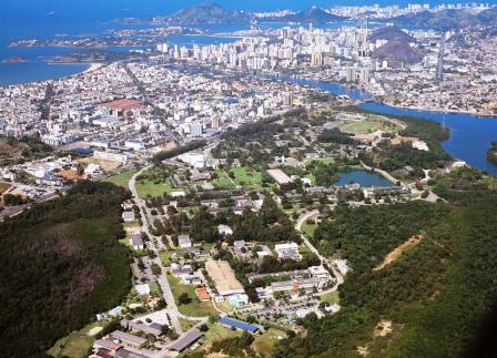 Imagem de uma cidade com muitas edificações juntas, areas verdes e o mar azul