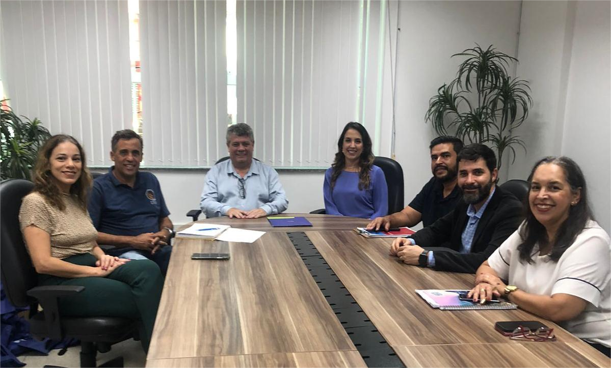 Da esquerda para a direita, Camila Fregona, Hélio Marchioni, o reitor Eustáquio de Castro, Maíra Bittencout, Leandro Marques, David Moraes e Thereza Marinho. Na foto, os participantes da reunião sentados em volta da mesa.