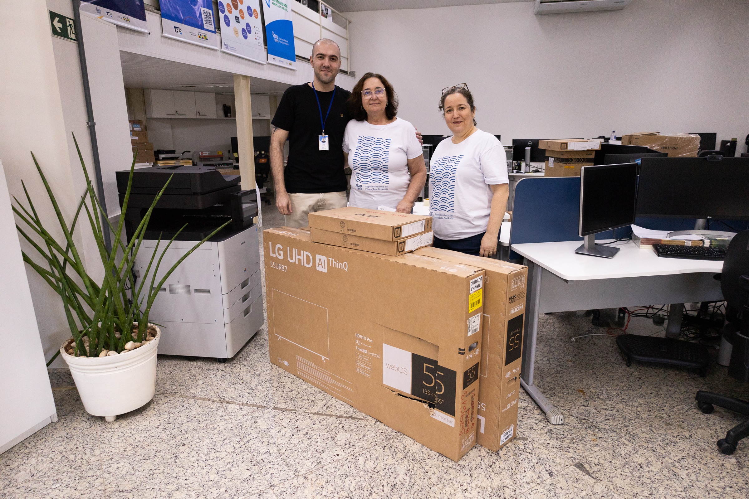 O coordenador do Polo de Baixo Guandú, Marcio Guilherme Marques, recebeu os equipamentos da superintendente de Educação a Distância, Maria Auxiliadora Corassa, e da diretora Acadêmica, Andreia Lins. O coordenador do Polo de Baixo Guandú, Marcio Guilherme Marques, a superintendente de Educação a Distância, Maria Auxiliadora Corassa, e a diretora Acadêmica, Andreia Lins, posam com as caixas dos equipamentos na sala da Sead.