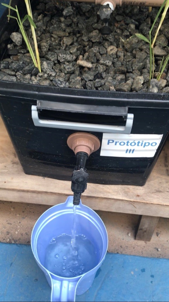 Filtro de biocarvão com uma torneira de onde sai água limpa Foto de uma caixa de biocarvão com uma torneira de onde sai água limpa caindo em um recipiente azul
