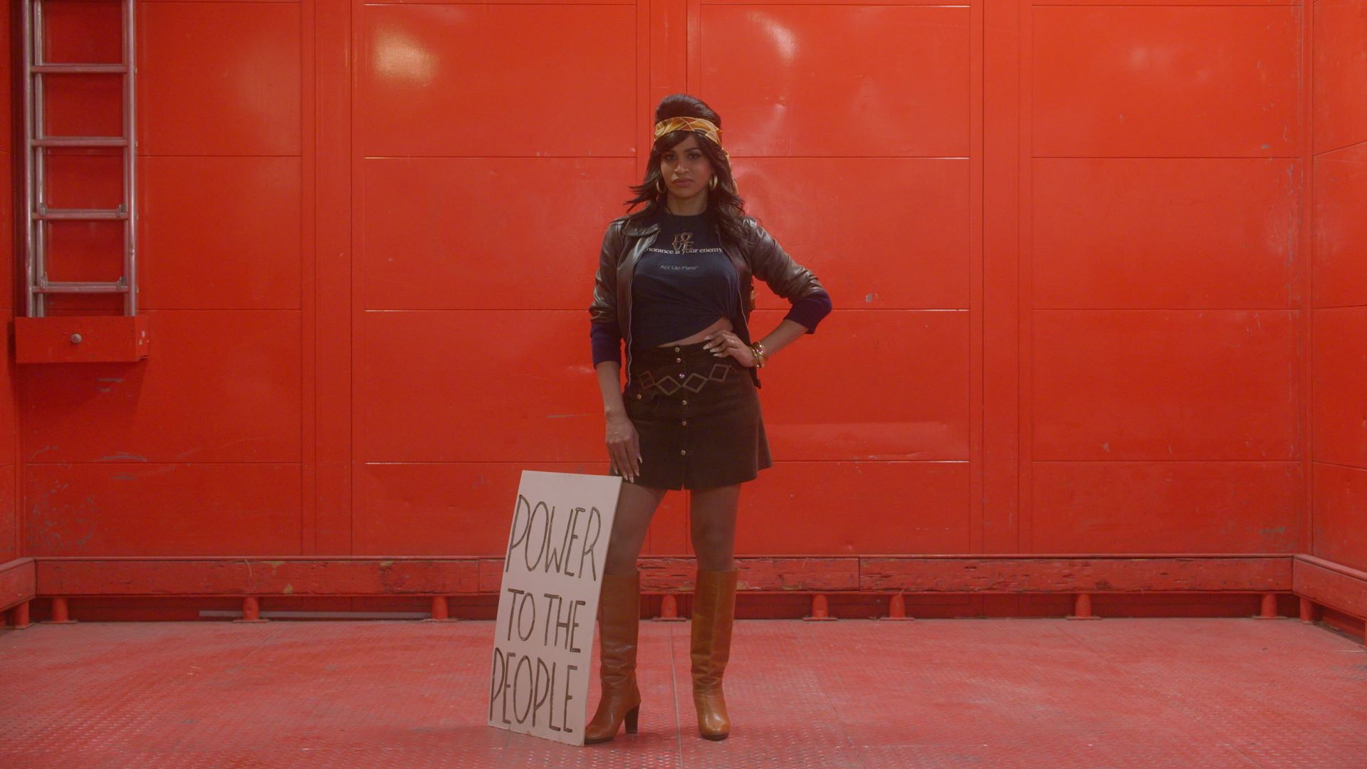 Cena de Orlando, minha biografia política Cena do filme Orlando, minha biografia política, na qual aparece uma pessoa trans em pé. Apoiado em sua perna há um cartaz onde se lê power to the people (poder para as pessoas)