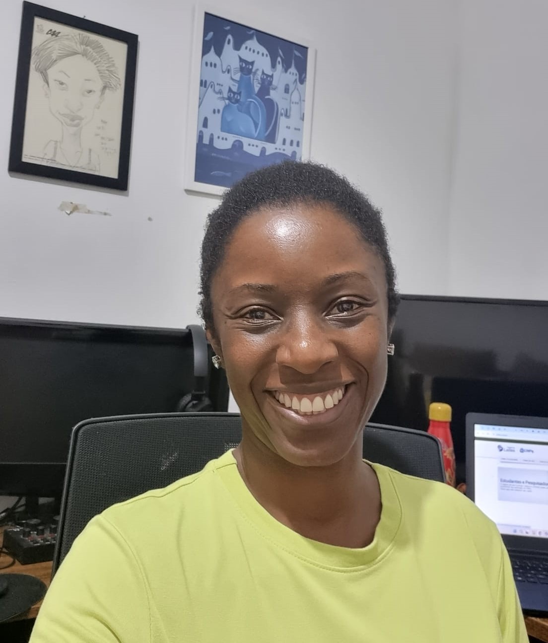 Tatiana Souza Foto da professora Tatiana Souza sorrindo para a câmera em uma sala com computadores