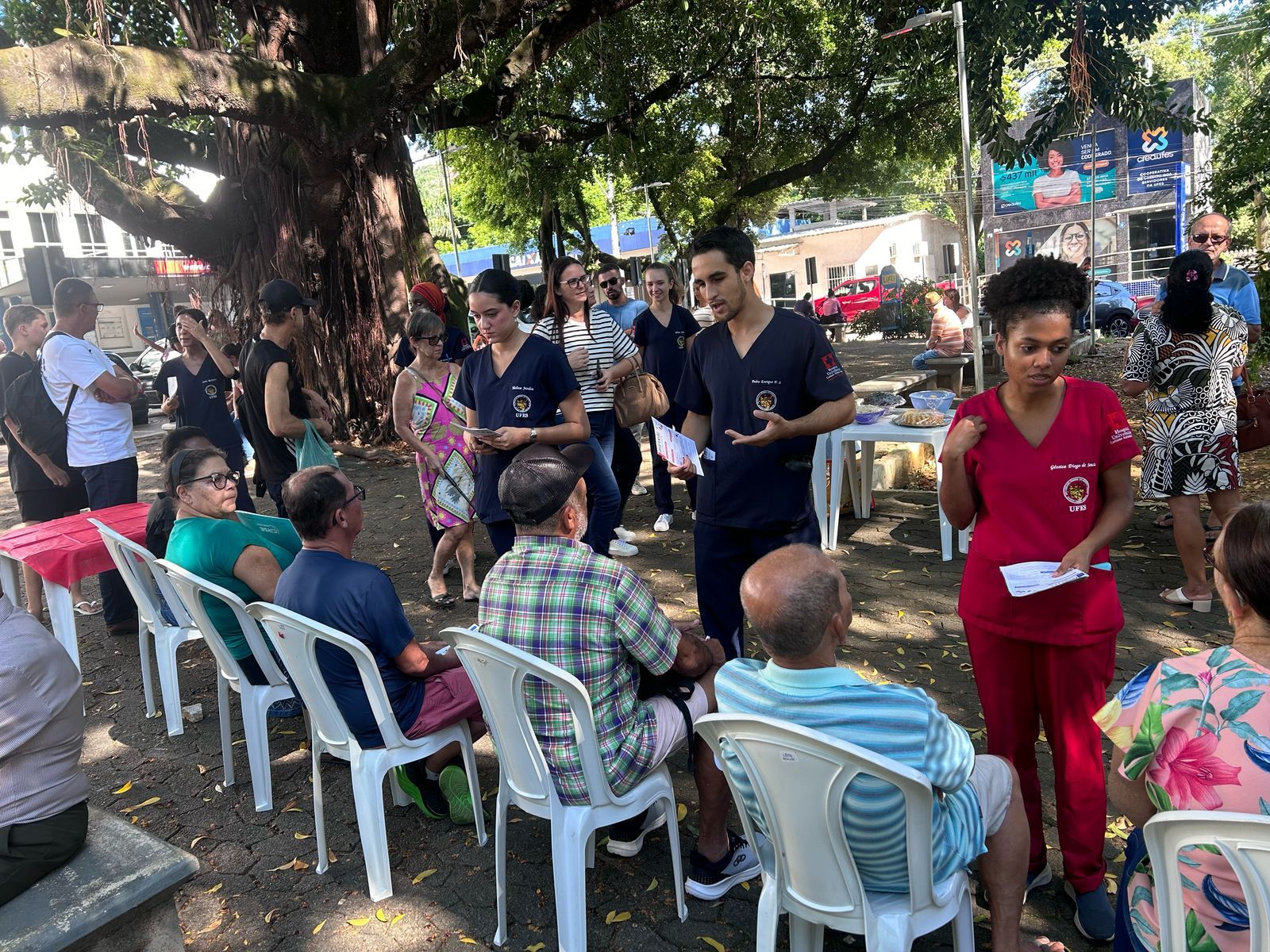 Cerca de 100 pessoas foram atendidas durante a ação Grupo de estudantes atendendo várias pessoas sentadas em cadeiras