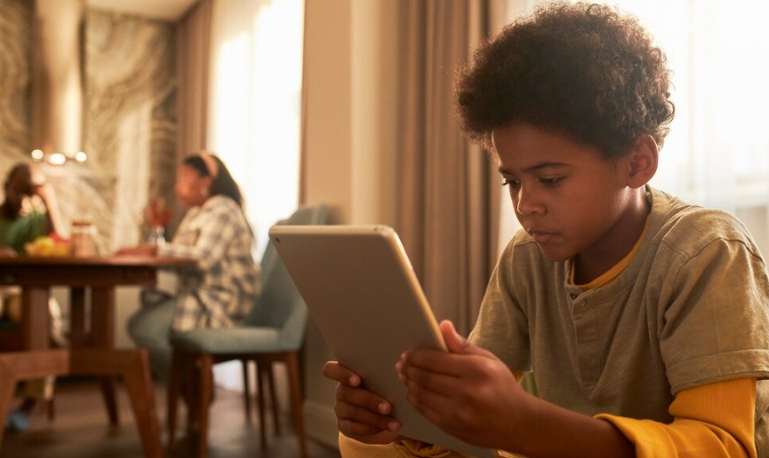 Imagem de um adolescente negro olhando a tela de um tablet
