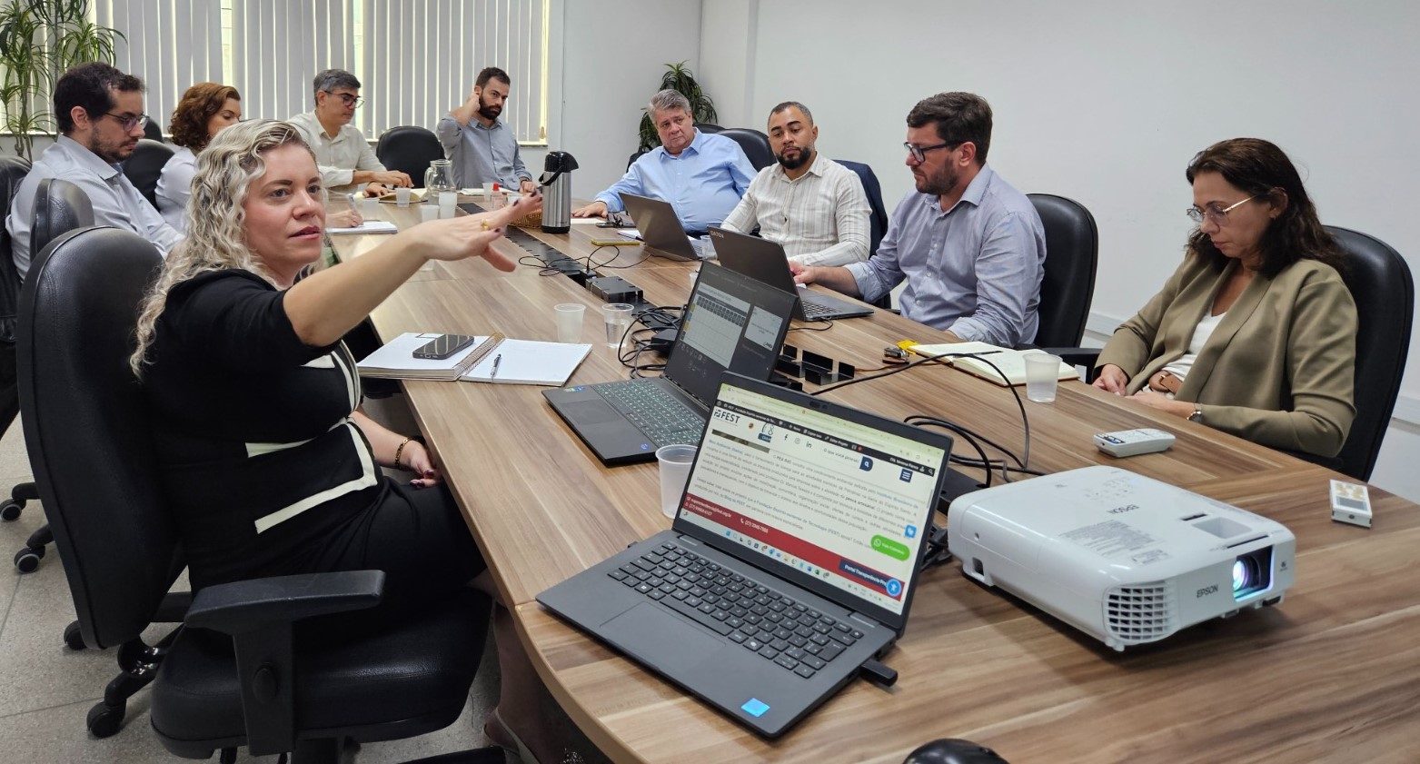 Foto da reunião, com todos os participantes reunidos em torno da mesa