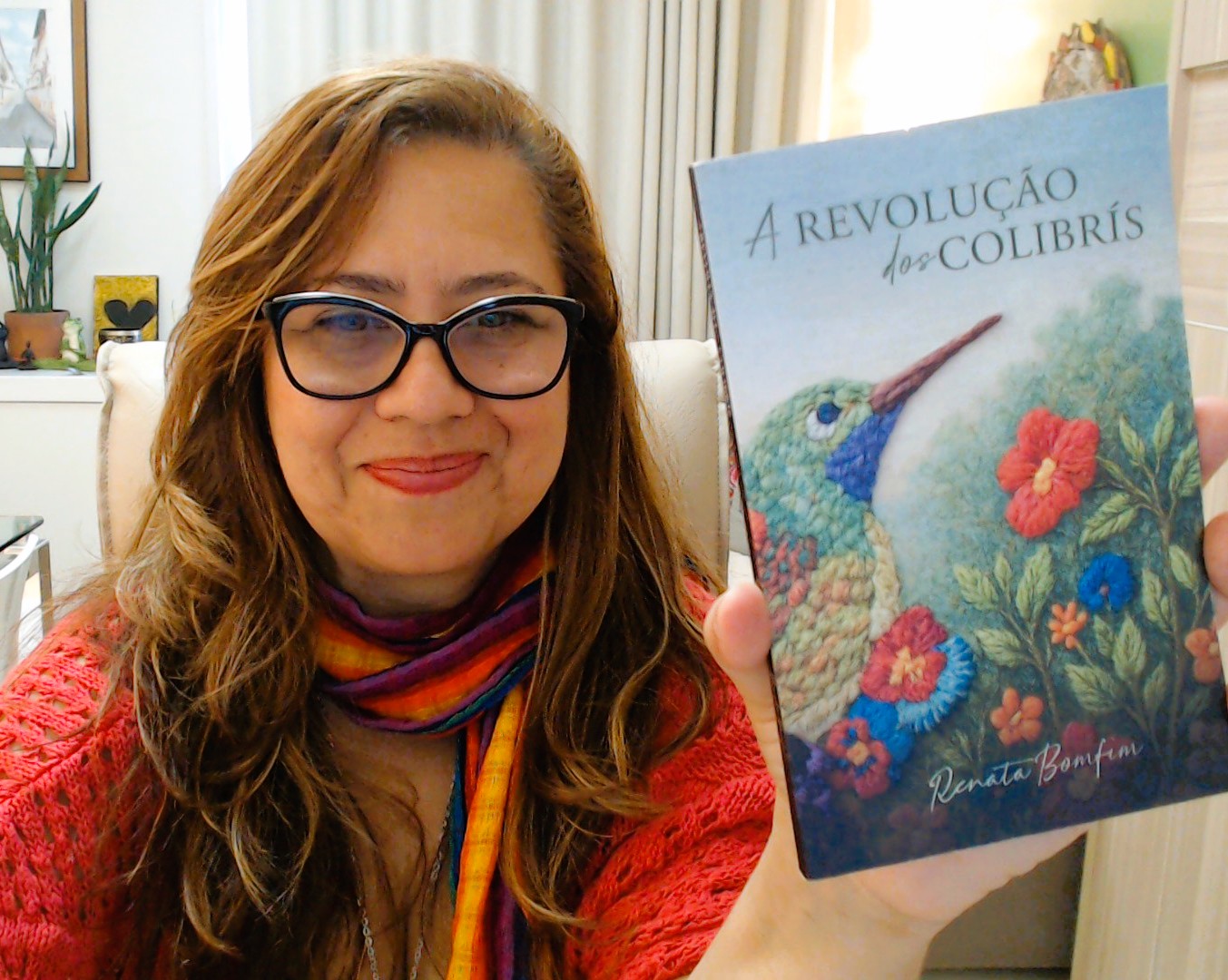 Autora posa segurando um exemplar do livro