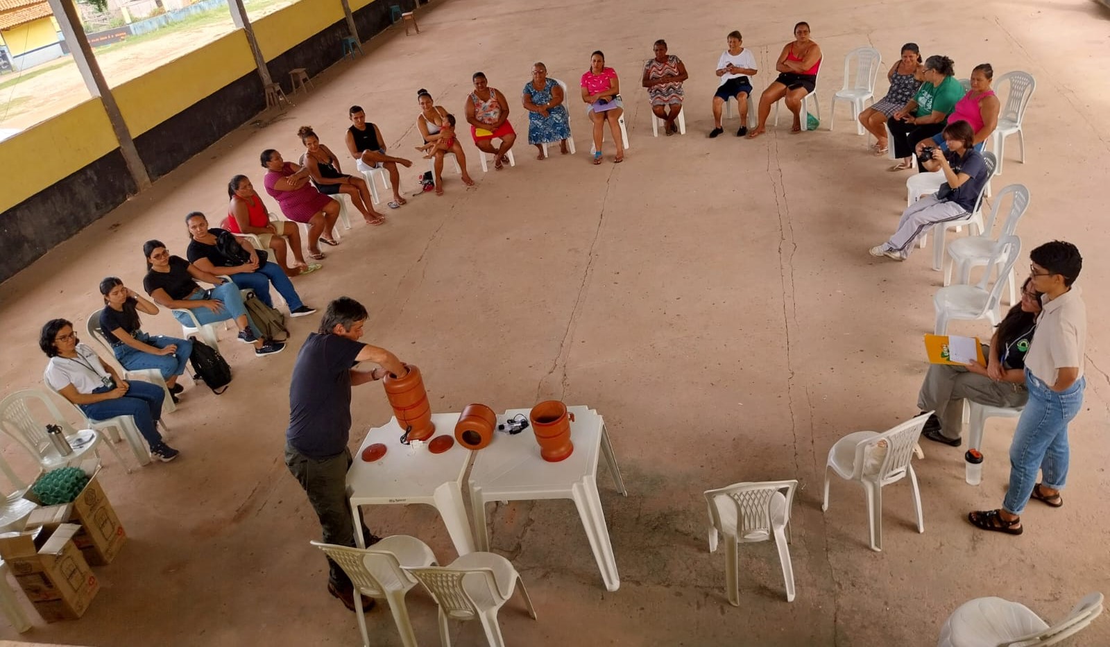 Moradores de Santarém sentados em uma grande roda vendo o professor ensinar a montagem do filtro