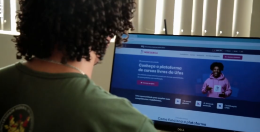 Foto de um rapaz de frente para o computador olhando para a página da plataforma