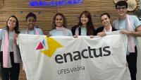 Estudantes exibem a bandeira da Enactus Ufes e os troféus