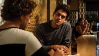 Cena de Ruas da Glória, na qual aparecem dois personagens conversando em uma mesa de bar