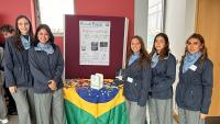 Foto da equipe envolta de uma mesa coberta com a bandeira do Brasil e o prêmio sobre ela