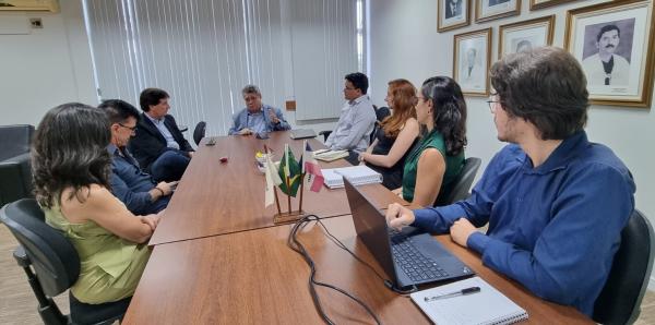 Foto da reunião de sexta-feira, com todos os presentes sentados em torno da mesa da sala de reuniões