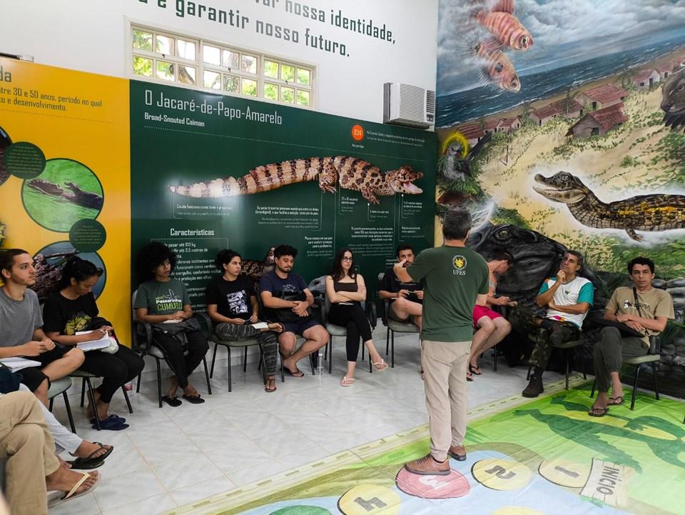 Foto dos estudantes ouvindo uma palestra em uma sala do parque