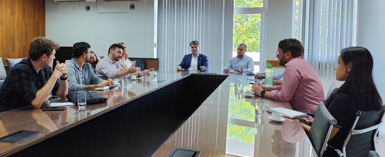 Foto dos participantes sentados à mesa de reunião 