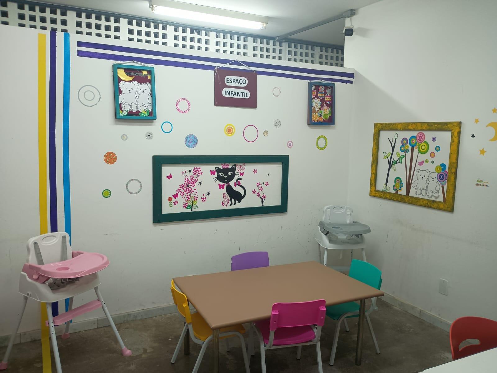 Foto do espaço com mesas e cadeiras para uso das crianças