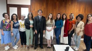 Foto das equipes da Siac e da Defensoria Pública, com a pessoas posando, em pé, na sala de reuniões da Reitoria.