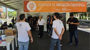 Foto da entrada da tenda, onde há uma faixa na cor laranja, com o nome da Jornada