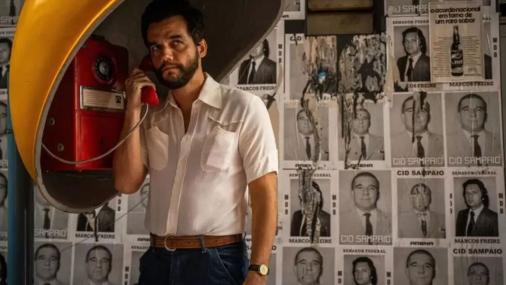 Cena de O Agente Secreto em que o personagem principal aparece usando o telefone de um orelhão