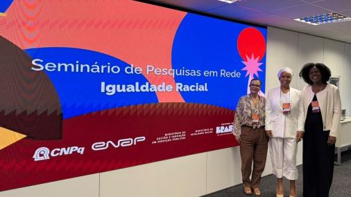 Foto das professores em frente ao painel do evento