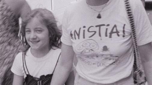 Foto de uma mulher vestindo uma camiseta em que se lê "anistia", ao lado de uma menina